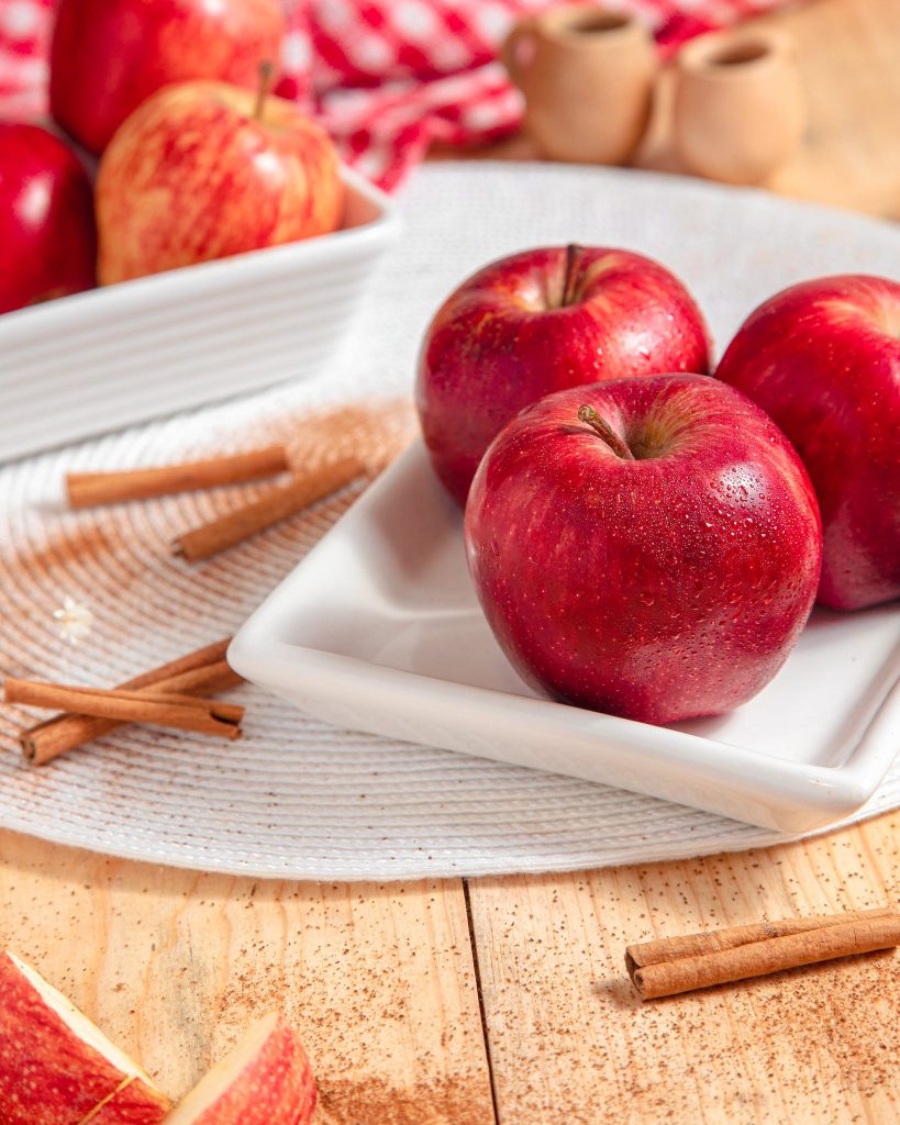 Red Apples on a Ceramic Plate Near Cinnamon Sticks